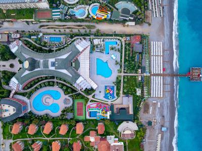 Letecký pohled na resort s několika bazény, budovami a přímým přístupem na pláž.