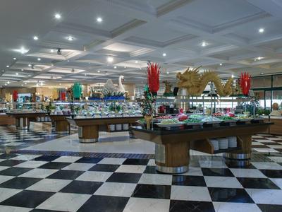 Velká bufetová oblast s kulatými stoly zdobenými květinami a mnoha pokrmy.