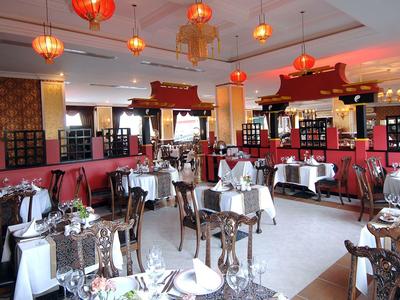 Elegantní restaurace s dřevěným nábytkem, bílými ubrusy a červenými lampiony zavěšenými ze stropu.