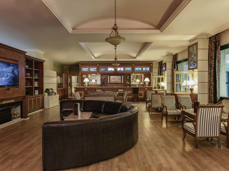 Pohodlný hotelový salonek s posezením, barem a dřevěným nábytkem za teplého osvětlení.