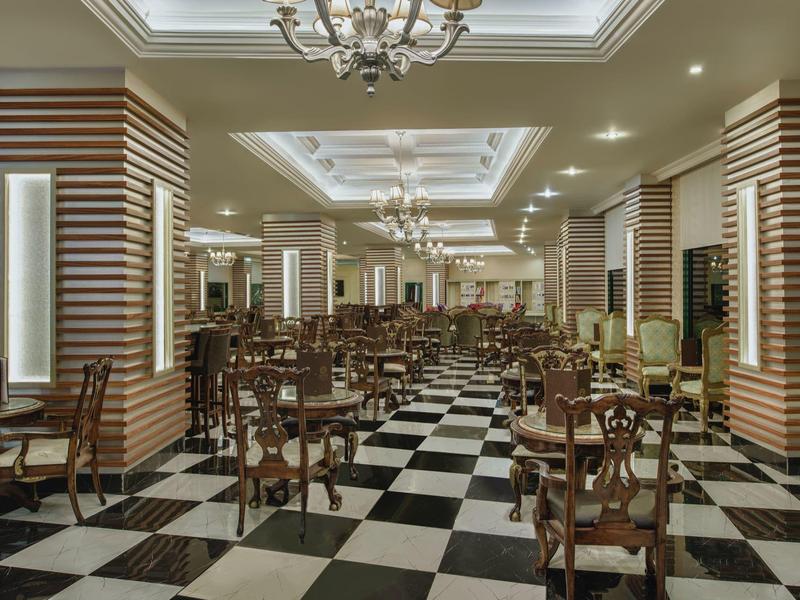 Elegantní jídelna se zdobenými židlemi, černobílou šachovnicovou podlahou a stropním osvětlením.