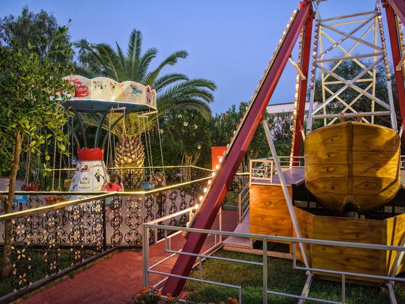 Opuštěný zábavní park se starým kolotočem a žlutou houpačkou při západu slunce.