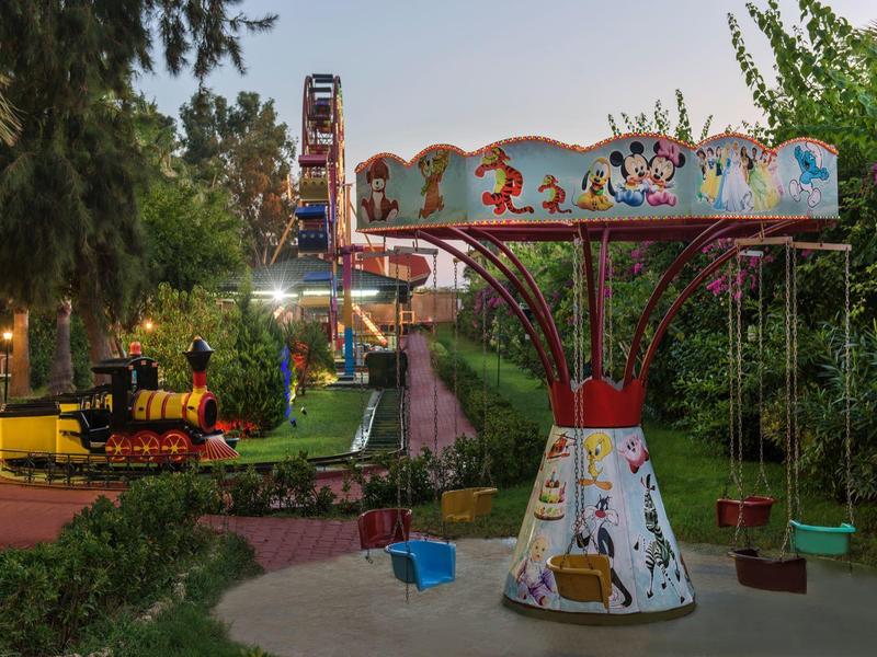 Empty carousel with colorful seats and locomotive in park at dusk.
