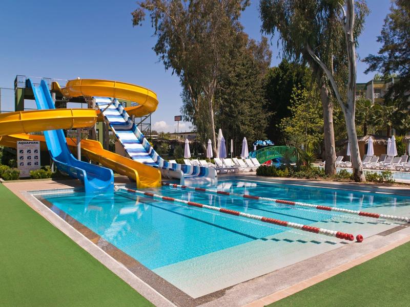 Clear swimming pool with water slides and sun loungers in a sunny holiday resort.