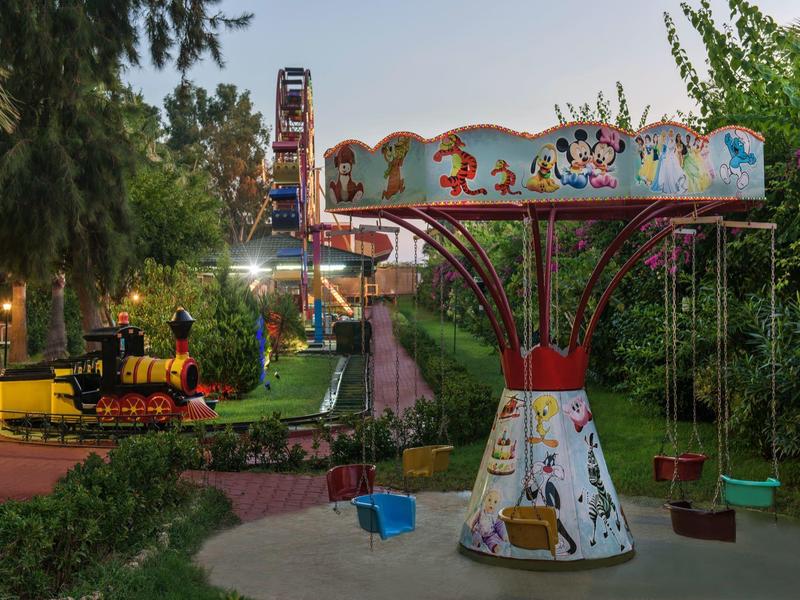 Children's swing and miniature steam train in park at dusk