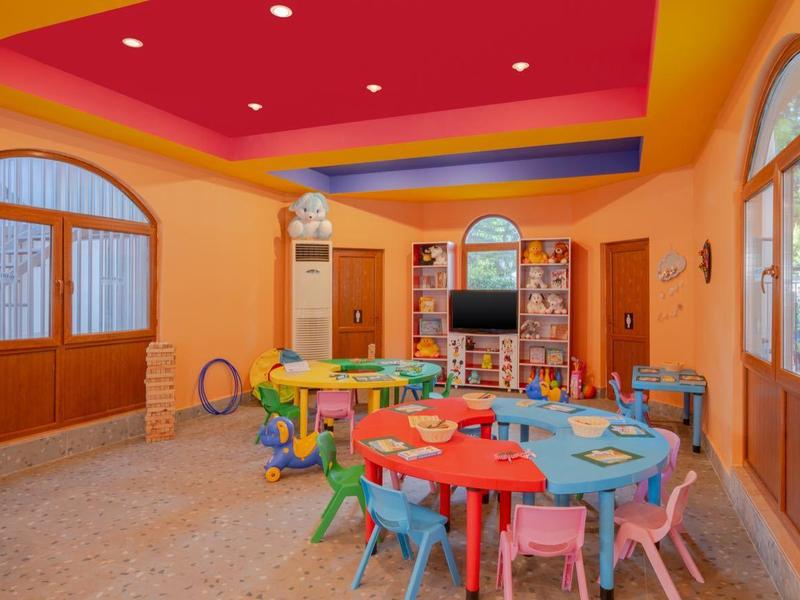 Colorful kid-friendly playroom with tables, chairs, and slide in a hotel.