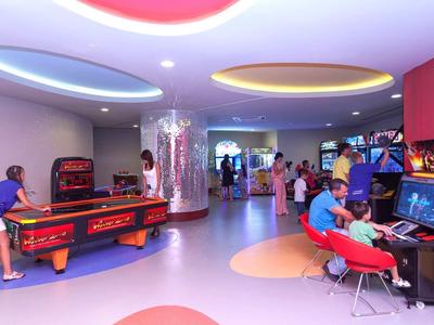 Sala giochi colorata con biliardo, arcade e persone in vacanza.