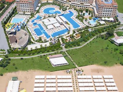 Vista aerea di un grande complesso alberghiero con piscine e spiaggia attrezzata.