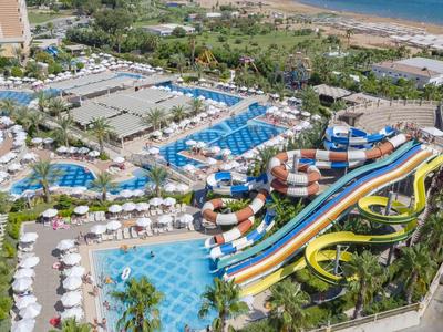 Complesso alberghiero con piscine, scivoli d'acqua colorati e vista sul mare.