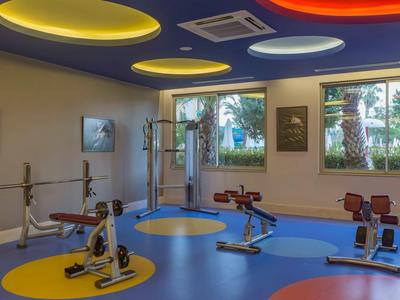 Interior de un gimnasio con suelo colorido, equipo de entrenamiento y grandes ventanas