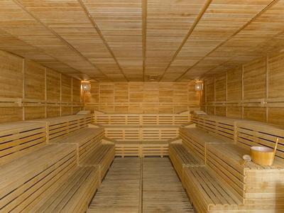 Interno spazioso di una sauna in legno con panche ai lati e accessori tradizionali.
