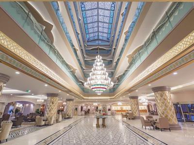Atrio dell'hotel luminoso con un grande lampadario e soffitto in vetro.