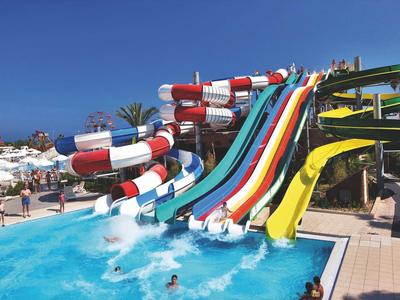 Varias toboganes de agua coloridos que desembocan en una piscina en un parque acuático.
