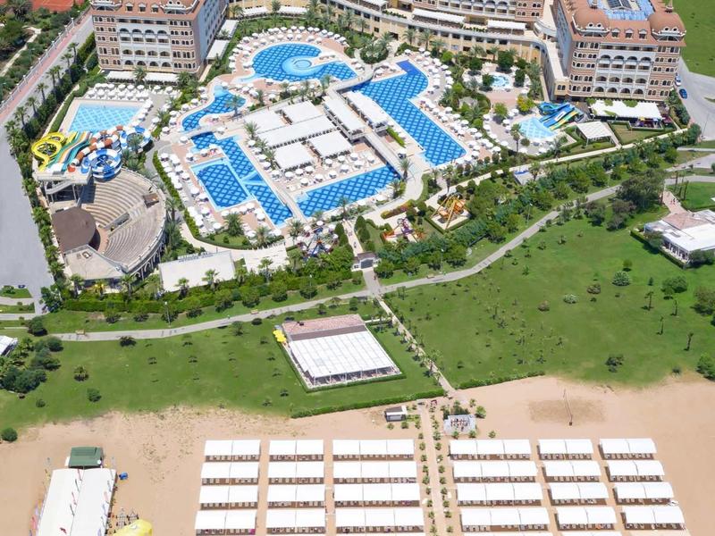 Vista aerea di un grande complesso alberghiero con piscine e spiaggia attrezzata.