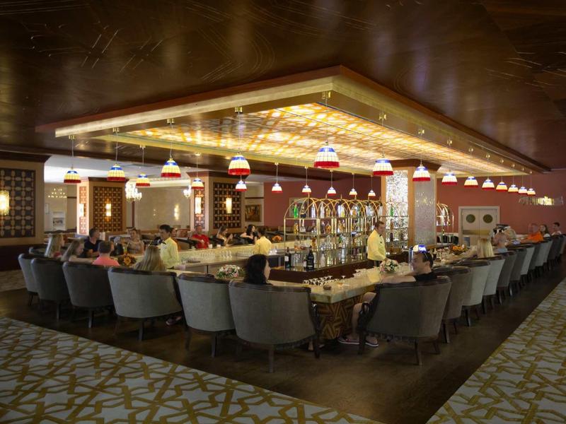 Sala da pranzo elegante con grandi tavoli, sedie comode e illuminazione calda.