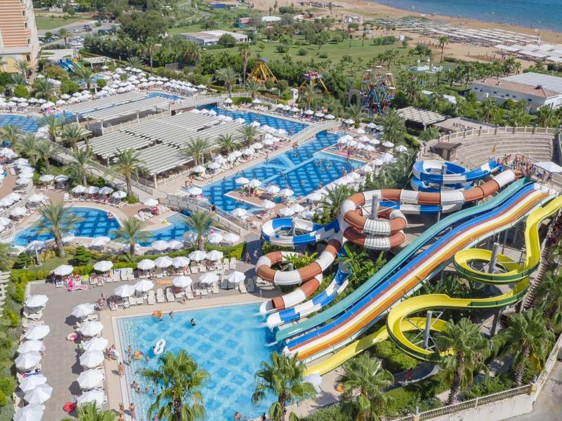 Complesso alberghiero con piscine, scivoli d'acqua colorati e vista sul mare.