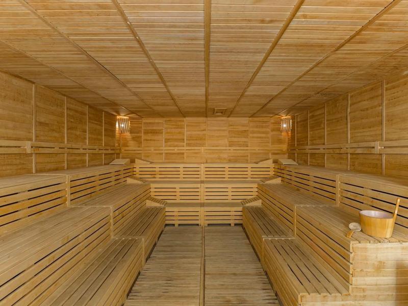 Interno spazioso di una sauna in legno con panche ai lati e accessori tradizionali.