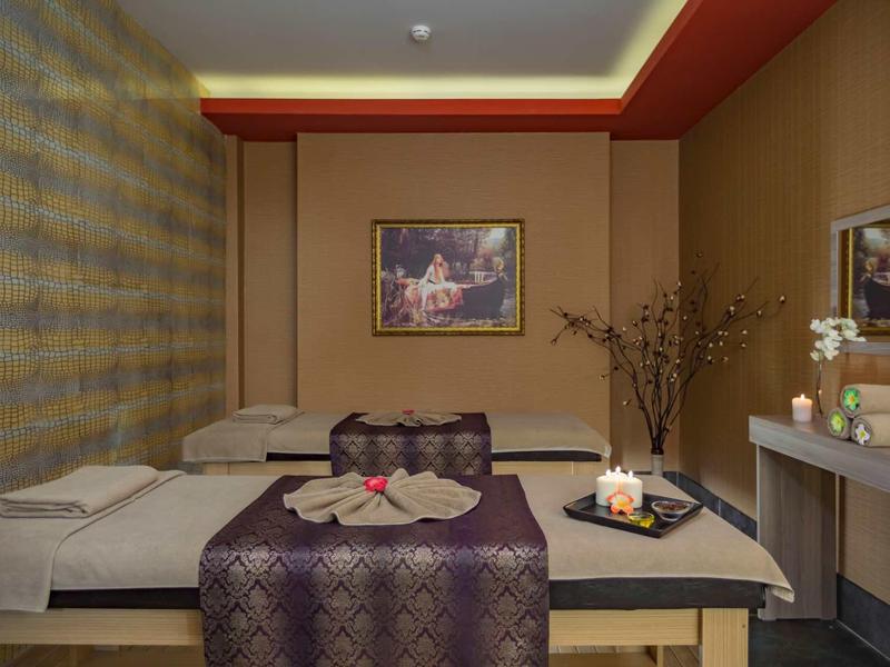 Sala massaggi con lettini, asciugamani piegati e decorazioni rilassanti.