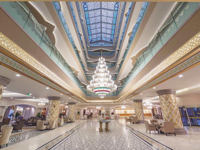 Atrio dell'hotel luminoso con un grande lampadario e soffitto in vetro.