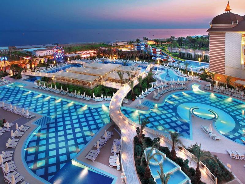 Ampio complesso alberghiero con piscine illuminate di notte vicino al mare.