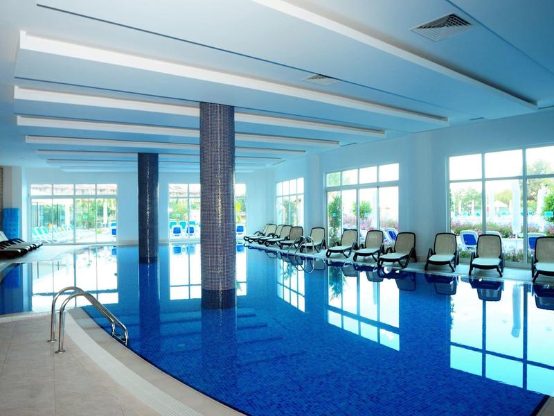 Piscina interna luminosa con lettini e grandi finestre