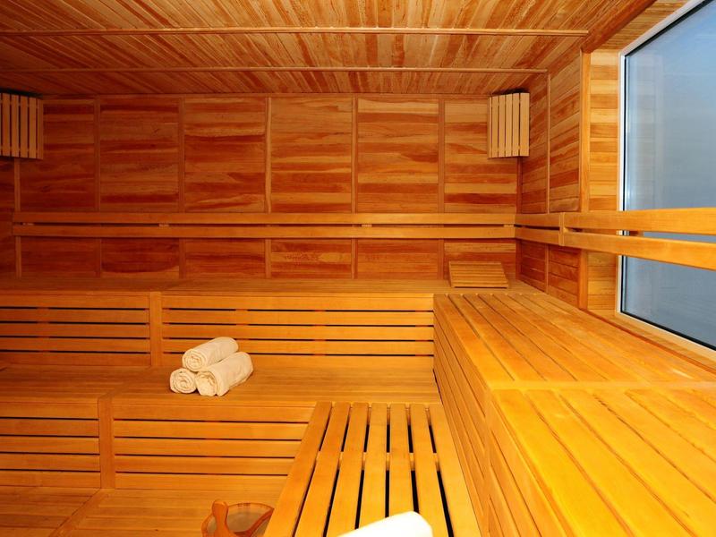 Sauna luminosa con pareti in legno, panca e grande finestra
