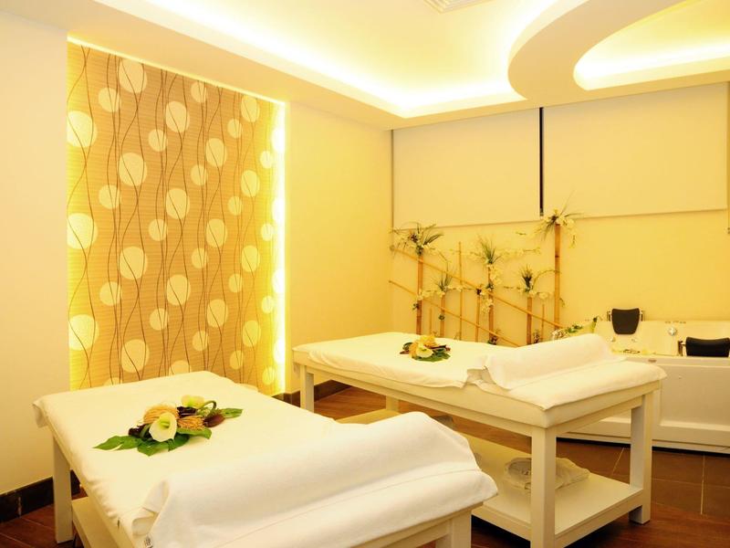 Stanza spa luminosa con due lettini da massaggio, decorata con fiori e luce soffusa.