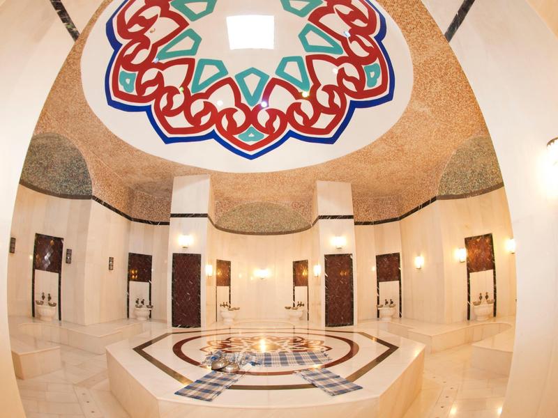 Ampia sala spa con fontana centrale a mosaico e decorazione colorata sul soffitto.