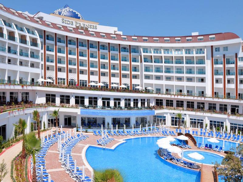 Hotel moderno con grande piscina curva e numerose sdraio blu.