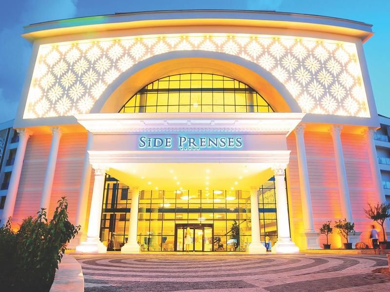 Ingresso dell'hotel illuminato con colonne e grande finestra ad arco al tramonto.