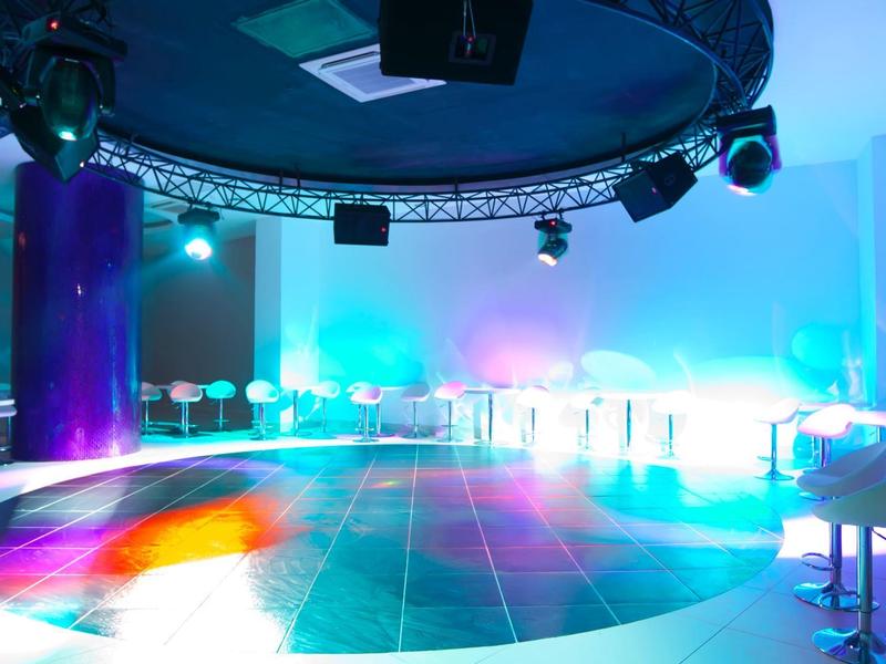 Sala party moderna e illuminata con pista da ballo e luci colorate.