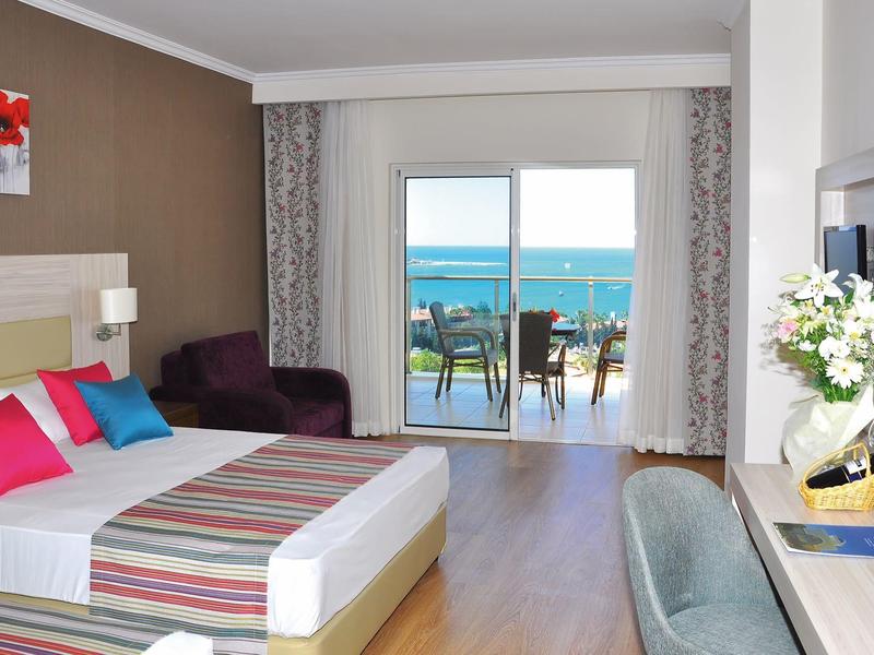 Camera d'hotel moderna con balcone e vista mare, luminosa e arredata con comfort.