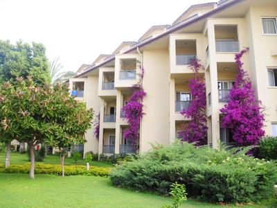 Mehrstöckiges Hotelgebäude mit blühenden Pflanzen und gepflegtem Garten