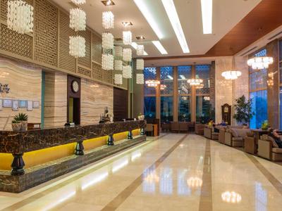 Ampia hall d'hotel con lampade da soffitto moderne, lunghe panche e grandi finestre.