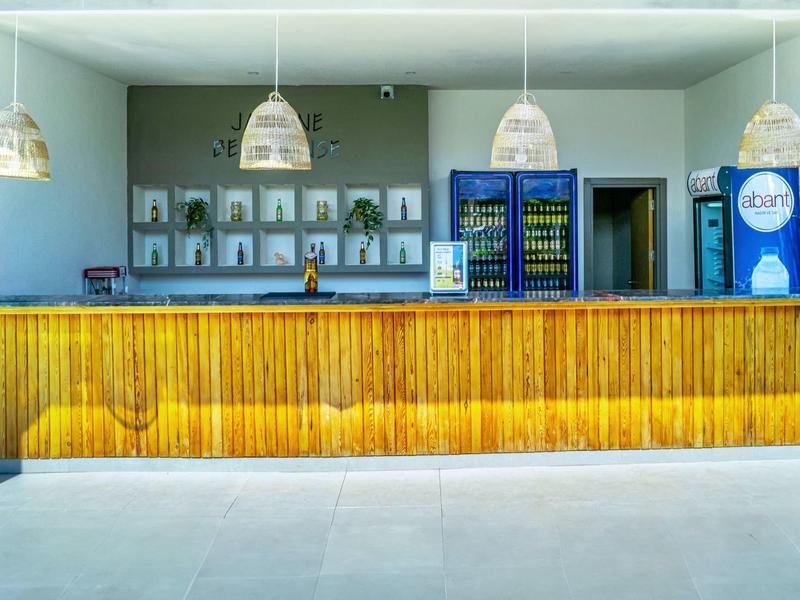 Bar aperta con banco in legno e frigorifero in un ambiente esterno moderno.