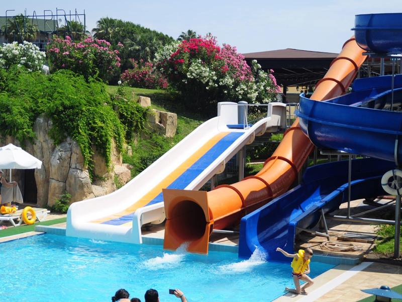 Scivoli d'acqua colorati conducono a una piscina limpida circondata da vegetazione tropicale.