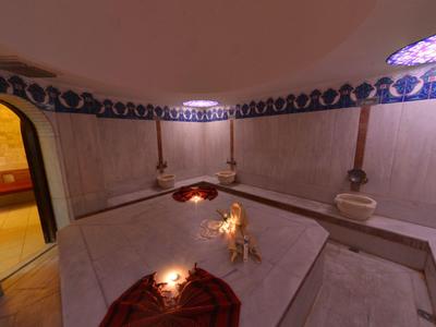 Interieur van een traditionele hammam met stenen banken en muren versierd met blauwe tegels.