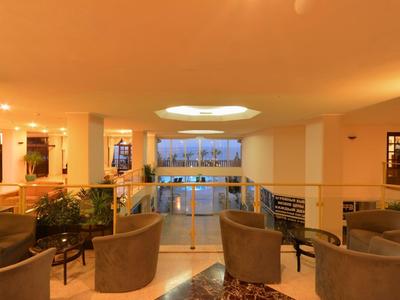 Gezellige hotel lounge met stoelen, tafels en uitzicht op het zwembad bij schemering.