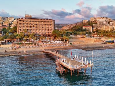 Hotel met zandstrand, steiger en ligstoelen bij kustplaats bij zonsondergang.
