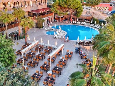 Area piscina dell'hotel con piscina circolare, ombrelloni e posti a sedere all'aperto in un giardino
