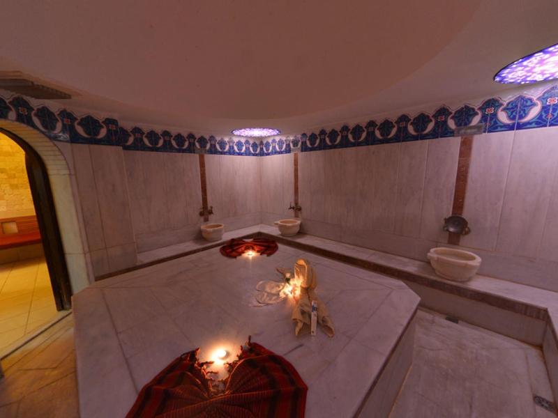 Interieur van een traditionele hammam met stenen banken en muren versierd met blauwe tegels.