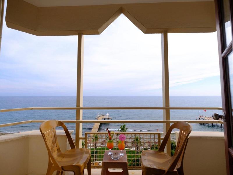 Balkon met twee stoelen en een klein tafeltje met drankjes, uitzicht op zee.