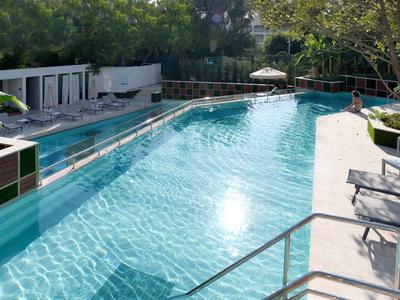 Piscina all'aperto con acqua limpida, circondata da lettini e vegetazione.