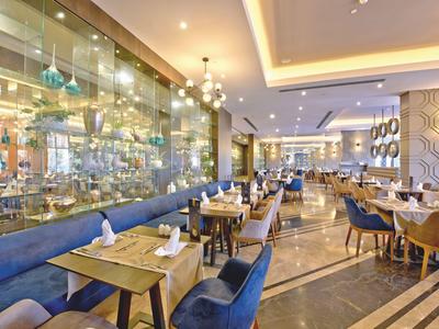 Zona pranzo moderna dell'hotel con sedie blu, tavoli in legno e illuminazione elegante.