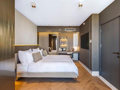 Camera d'hotel moderna con letto grande, pavimento in legno e ambiente elegante.