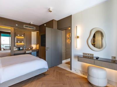 Camera d'hotel moderna con letto matrimoniale, specchio e pavimenti in legno chiaro.