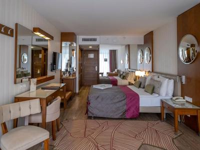 Chambre d'hôtel moderne avec lit double, coin salon et bureau dans des tons chauds.