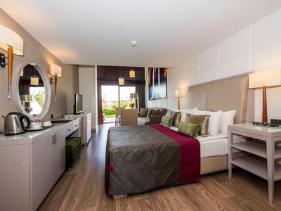 Chambre d'hôtel moderne avec lit double, bureau, chaises et accès à une terrasse.