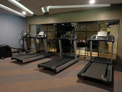 Salle de sport d'hôtel avec plusieurs tapis roulants face à une grande fenêtre miroir.