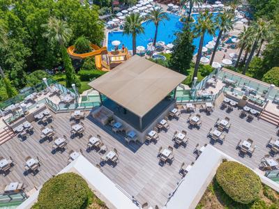 Vue aérienne d'une piscine d'hôtel avec chaises longues et un pavillon ombragé sur la terrasse.